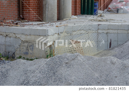 Construction debris and waste at the construction site. Red brick building. Concrete foundation. Construction Industry. Architecture. No people. Construction debris and waste at the construction site. Red brick building. Concrete foundation. Construction Industry. Architecture. No people. 81821435