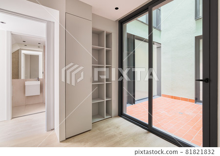 Interior of modern empty room in refurbished apartment with big black frame of windows, wardrobe and view to the bathroom. Interior of modern empty room in refurbished apartment with big black frame of windows, wardrobe and view to the bathroom. 81821832