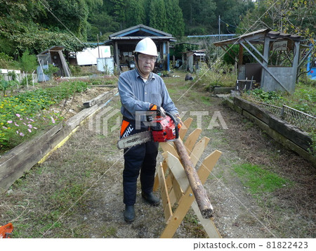 一個男人試圖用電鋸切割原木，退休後搬到鄉下，將木材作為木工的愛好 81822423