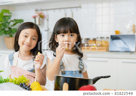 Portrait two Asian sister playing and care together eating at home kitchen. Portrait two Asian sister playing and care together eating at home kitchen. 81822549