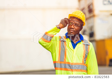 Black African happy worker working in logistic shipping standing confident smart looking containers at port cargo shipping work industry. Black African happy worker working in logistic shipping standing confident smart looking containers at port cargo shipping work industry. 81822563
