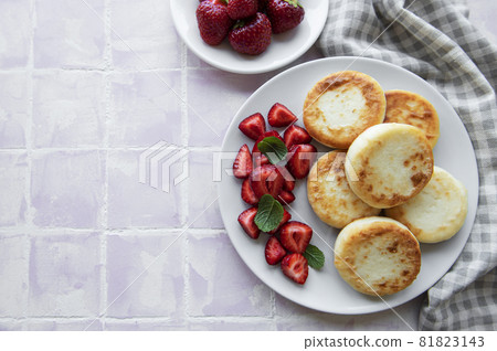 Cottage cheese pancakes, ricotta fritters on ceramic plate with fresh strawberry. Cottage cheese pancakes, ricotta fritters on ceramic plate with fresh strawberry. 81823143