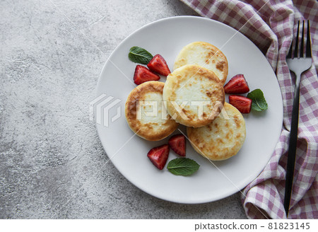 Cottage cheese pancakes, ricotta fritters on ceramic plate with fresh strawberry. Cottage cheese pancakes, ricotta fritters on ceramic plate with fresh strawberry. 81823145