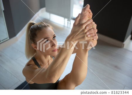 Close-up portrait of young sportive happy girl, coach in sportswear doing yoga stretching exercises on sports mat at meditation center, indoors. Concept of healthy lifestyle 81823344