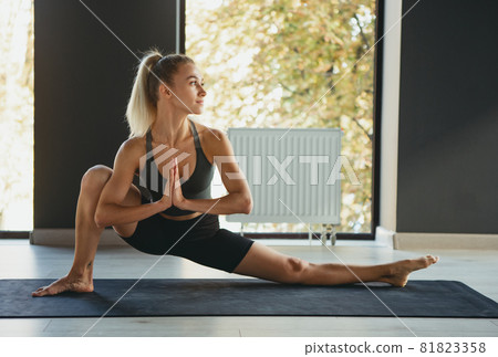 Yoga master. Portrait of young slim sportive woman in sportswear doing complex of movements on sports mat at yoga meditation center. Concept of healthy lifestyle Yoga master. Portrait of young slim sportive woman in sportswear doing complex of movements on sports mat at yoga meditation center. Concept of healthy lifestyle 81823358
