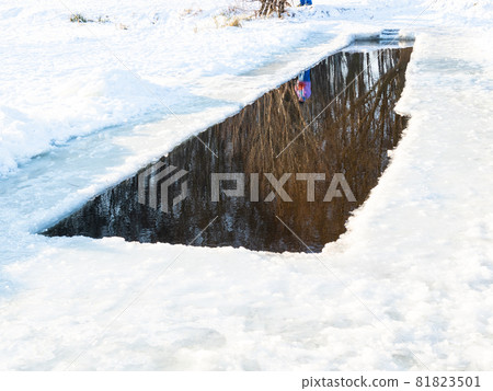 swimming ice-hole in frozen snow-covered pond in city park on cold sunny winted day swimming ice-hole in frozen snow-covered pond in city park on cold sunny winted day 81823501