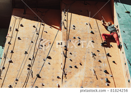 One Caucasian man professional rock climber workouts on climbing wall at training center in sunny day, outdoors. Concept of healthy lifestyle, power, strength, motion. 81824256