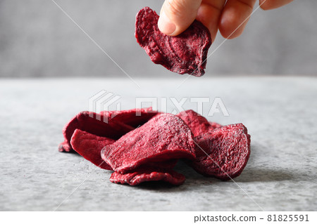 Take a piece vegetable beetroot chips on a gray background. Take a piece vegetable beetroot chips on a gray background. 81825591