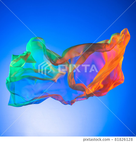 Colored flying silk textile. Piece of elegant transparent fabric isolated over blue studio background 81826128