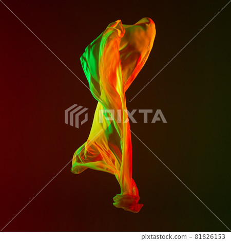 Smooth elegant transparent multicolored yellow green flying piece of fabric isolated on dark studio background 81826153