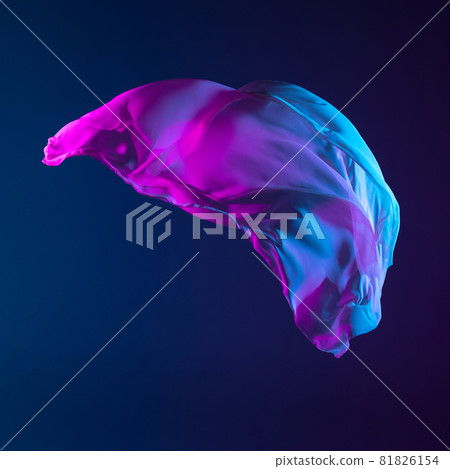 Smooth elegant transparent gradient blue piece of fabric isolated on dark blue studio background. Texture of flying silk cloth 81826154