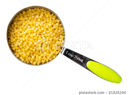 top view of uncooked ptitim (Israeli couscous) in measuring cup cutout on white background top view of uncooked ptitim (Israeli couscous) in measuring cup cutout on white background 81826208