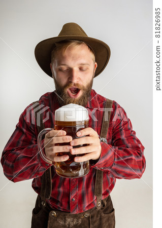 Half-length portrait of bearded man in hat and traditional Bavarian costume holding huge mug, glass of light frothy beer isolated over white background. Flyer Half-length portrait of bearded man in hat and traditional Bavarian costume holding huge mug, glass of light frothy beer isolated over white background. Flyer 81826985