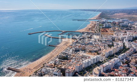 Beautiful aerial cityscapes of the tourist Portuguese city of Quarteira. On the seashore during the beach season with tourists who are sunbathing. 81827347