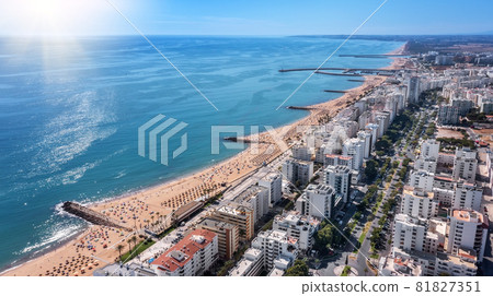 Beautiful aerial cityscapes of the tourist Portuguese city of Quarteira. On the seashore during the beach season with tourists who are sunbathing. 81827351