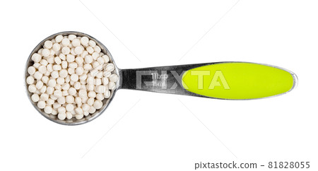 top view of uncooked ptitim (pearl couscous) in measuring spoon cutout on white background 81828055