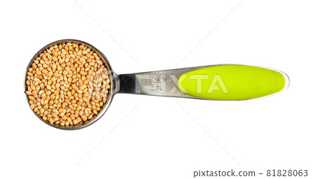 top view of unhulled yellow proso millet seeds in measuring tablespoon cutout on white background 81828063