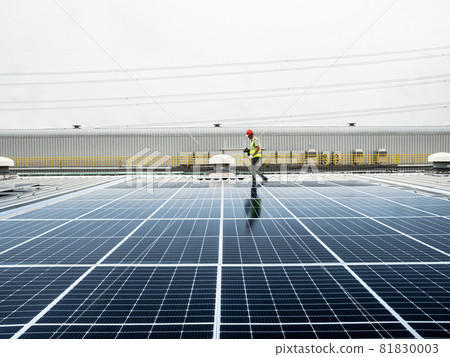 male engineer checks a photovoltaic (solar) plant and uses a recording tablet. mechanic in protective helmet. Man in uniform holding tablet.. male engineer checks a photovoltaic (solar) plant and uses a recording tablet. mechanic in protective helmet. Man in uniform holding tablet.. 81830003