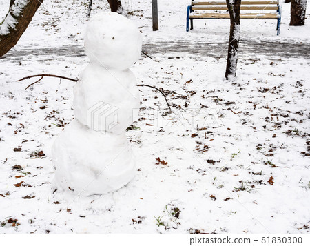 snowman from the first snow on snowy lawn in city park on cold autumn day 81830300
