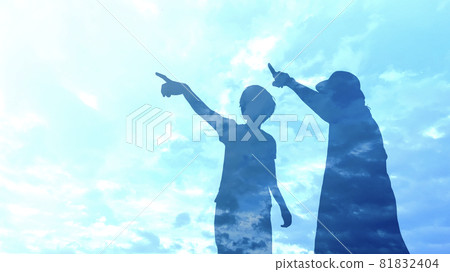 Silhouettes of two women pointing under the blue sky 81832404