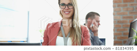 Young smiling businesswoman sits at working table on background of business office Young smiling businesswoman sits at working table on background of business office 81834395