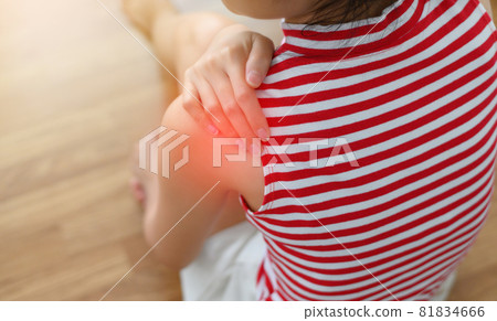 Back view of Asian woman hand touch to shoulder have pain sitting on the wooden floor. Health care and medical concept. 81834666