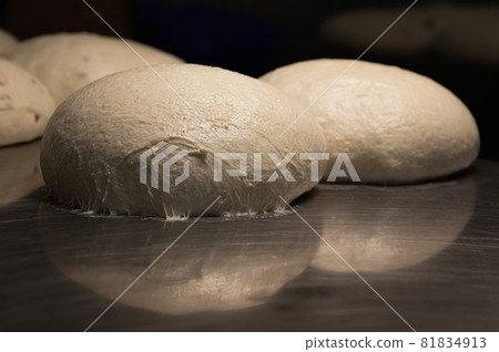 The uncooked round buns of dough are placed on a metal tray. Hamburger bun dough 81834913