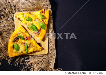 Two slices of pizza in a rustic style on a black background. Top view. Space for copying text Two slices of pizza in a rustic style on a black background. Top view. Space for copying text 81835307