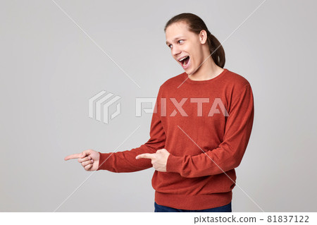 young man pointing finger away at empty space young man pointing finger away at empty space 81837122