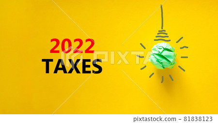 2022 taxes new year symbol. Words '2022 taxes', isolated on beautiful yellow background. Green light bulb icon. Business and 2022 taxes new year concept. Copy space. 81838123