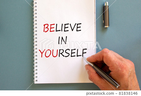 Male hand writing 'believe in yourself' on white note, isolated on blue background. Business concept. Male hand writing 'believe in yourself' on white note, isolated on blue background. Business concept. 81838146