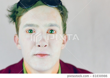 Guy with white makeup on face and green hair. 81838986