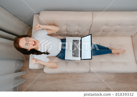An irritated woman sitting on the couch with a laptop. 81839332