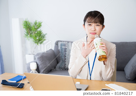 A woman who drinks tea at work to moisturize her throat A woman who drinks tea at work to moisturize her throat 81840217