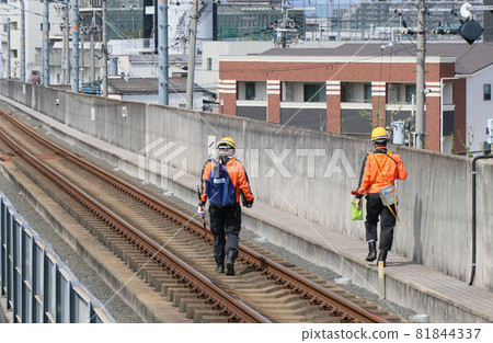A staff member inspecting the railroad tracks in the elevated section of JR West 81844337
