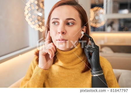 Lady with prosthesis arm inserting wireless earphones Lady with prosthesis arm inserting wireless earphones 81847797