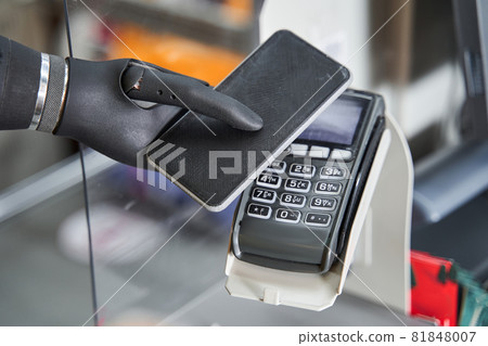 Woman with artificial limb paying contactless by smartphone 81848007