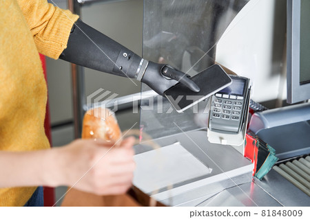 Consumer with implant hand keeping smartphone over cashier-machine 81848009