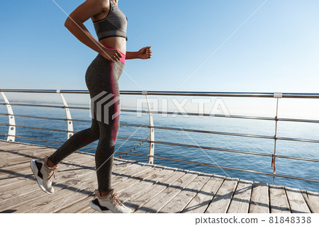 Cropped shot of female running along the seaside, jogging and working out near the sea Cropped shot of female running along the seaside, jogging and working out near the sea 81848338