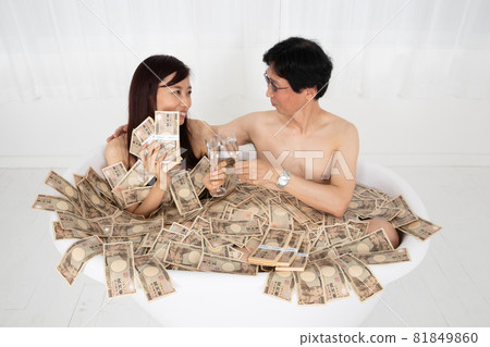 Bubbly men and women taking a wad of bills bath 81849860