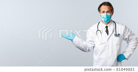 Covid-19, preventing virus, healthcare workers and vaccination concept. Skeptical and confused male doctor in medical mask and gloves, pointing left with dismay and frustrated, displeased with choice Covid-19, preventing virus, healthcare workers and vaccination concept. Skeptical and confused male doctor in medical mask and gloves, pointing left with dismay and frustrated, displeased with choice 81849881