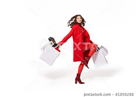 Woman in red coat running with white shopping bag Woman in red coat running with white shopping bag 81850288