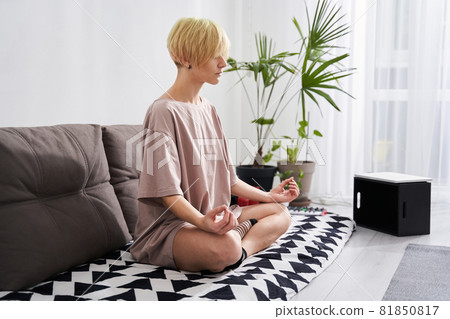 Woman meditating at her cozy living room 81850817