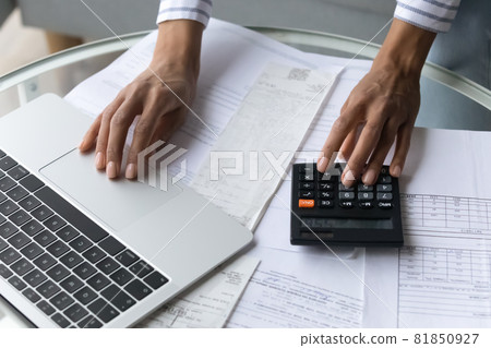 Black female hands using calculator and laptop at home office 81850927