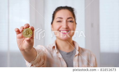 Blurred young brunette woman holding golden bitcoin in her hand Blurred young brunette woman holding golden bitcoin in her hand 81851673