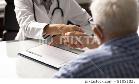 Senior man visiting doctor, shaking hands with young female therapist 81851823