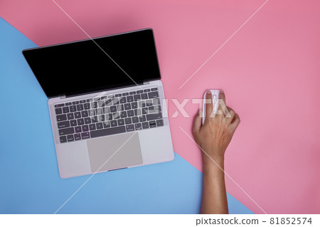 Man using laptop and wireless mouse on pink and blue background. copy space. Man using laptop and wireless mouse on pink and blue background. copy space. 81852574