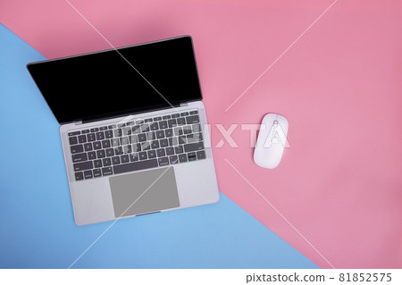 Laptop and wireless mouse on pink and blue background. copy space. top view. 81852575
