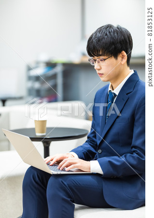 A businessman who uses a computer in a cafe A businessman who uses a computer in a cafe 81853125