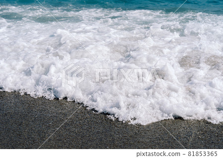 White foamy waves on sandy beach closeup. Seaside on sunny summer day. 81853365